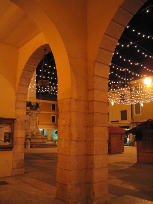 VISTA DELLA PIAZZA E DEL MONUMENTO AI CADUTI DA SOTTO I PORTICI